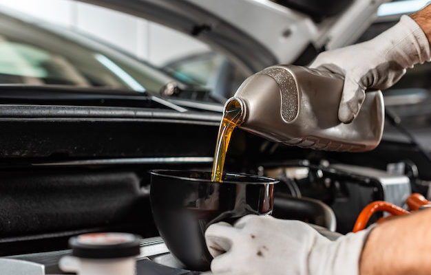 partial view of mechanic pouring motor oil at car engine