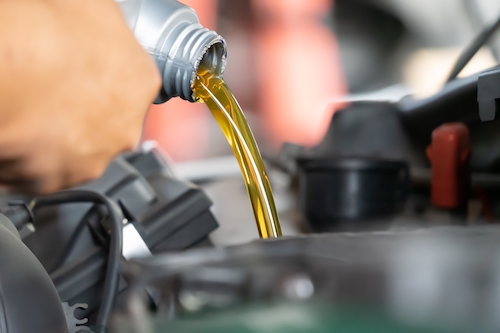 auto mechanic pouring motor oil